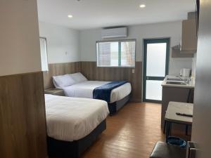 a hotel room with two beds and a kitchen at Conway Motel Manukau in Auckland