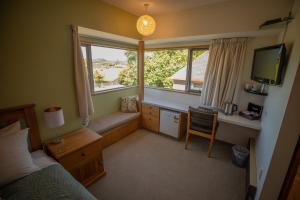 Schlafzimmer mit einem Bett, einem Schreibtisch und einem Fenster in der Unterkunft Woodland Glen Lodge B&B in Hokitika