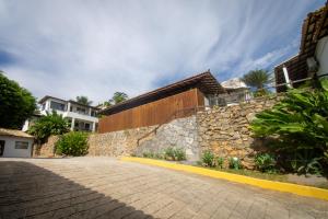 a stone wall next to a brick road at Pousada Gammel Dansk by Latitud Hoteles in Búzios