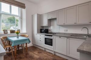 een keuken met witte kasten en een tafel met stoelen bij Wansfell Heights in Ambleside