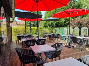 une terrasse avec des tables et des chaises et des parasols rouges dans l'établissement Logis Hotel & Restaurant de la Basilique, à Albert