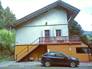 une voiture garée devant une maison avec balcon dans l'établissement Sacromonte Apart, à San Martín de los Andes