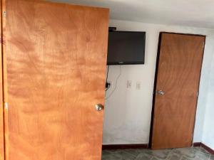 Habitación con puerta y TV en la pared en Hostal Inn II Rionegro en Rionegro