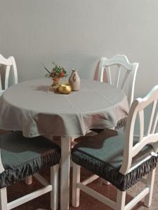 una mesa blanca con 2 sillas y una mesa con un jarrón en Apartamento piscina Santa Pola, en Santa Pola