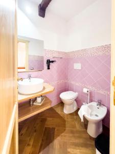 a pink bathroom with a sink and a toilet at La Torre del Pozzo Guest House in Bosa