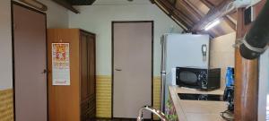 a kitchen with a refrigerator and a microwave at La Pirogue chez l'Happy qui chante in Haapiti