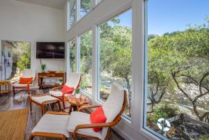 a room with large windows with chairs and a table at Sierra River House 5 min to Sequoia Park Entrance in Three Rivers