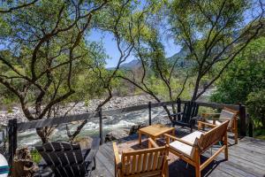 a deck with chairs and tables and trees at Sierra River House 5 min to Sequoia Park Entrance in Three Rivers