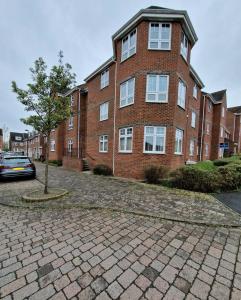a brick building with a tree in front of it at Impeccable 2-Bed Apartment in Newcastle upon Tyne in Newcastle upon Tyne