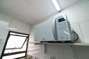 a microwave on a shelf in a room with a window at 52 LOFT quadruplo · LOFT perto da São Paulo EXPO edo metrô Jabaguara in São Paulo