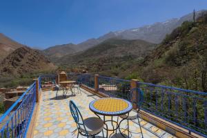 a patio with tables and chairs on a balcony with mountains at Atlas Haven in Imlil