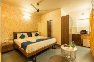 a bedroom with a bed and a table in it at Seasons Suites JP Nagar in Bangalore +1 photo