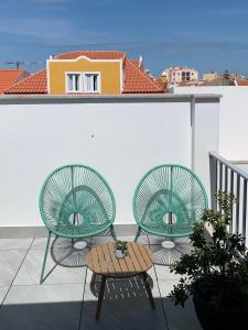 two green chairs and a table on a balcony at Peniche36 in Peniche