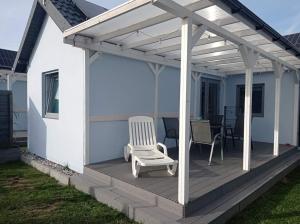 una terraza con pérgola blanca y una silla en Domki nad morzem, Laba Rusinowo koło Jarosławca,, en Rusinowo