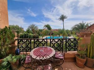 a table and chairs on a balcony with a pool at La Perle de Marrakech by Atlas Golf Resort in Marrakech