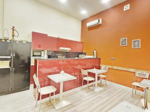 una cocina con mesas y sillas blancas y paredes rojas en ELYSIUM HOTEL en Baku