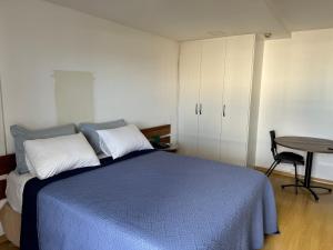 a bedroom with a blue bed and a table at Flat Particular Hotel Saint Paul in Brasilia