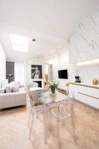 una sala de estar blanca con mesa de cristal y sillas en Native Apartments Starowiślna 43/15 en Cracovia