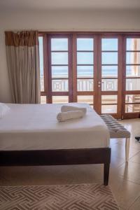 a bedroom with a bed and a large window at SANDS AND ROCKS APARTMENT in Mombasa