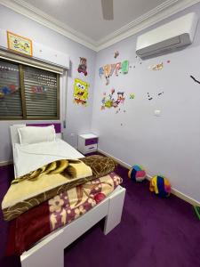 una camera con un letto in una stanza con moquette viola di Masa Aqaba Apartments ad Aqaba