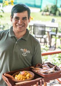 Een man met een dienblad met een bord met eten. bij ART HOUSE Hacienda San Antonio in Cajamarca