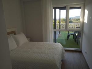 1 dormitorio con 1 cama y ventana con balcón en Casa Surf Lanzada, en Sanxenxo