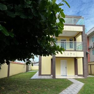 Una casa amarilla con balcón en la parte superior. en Pousada Pé na Areia Rio das Ostras en Rio das Ostras