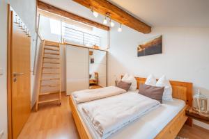 um quarto com uma cama com lençóis brancos e uma janela em Weissnhof em Samerberg