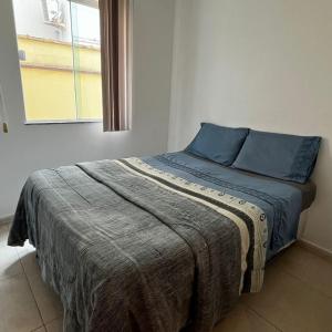 una camera da letto con un letto con cuscini blu e una finestra di Pousada Pé na Areia Rio das Ostras a Rio das Ostras