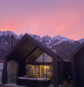 a house with mountains in the background at sunset at Luxury Alpine Retreat with a hot tub in Frankton