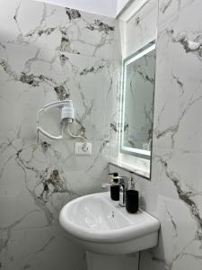 uma casa de banho branca com um lavatório e um espelho em Nika's Guest House em Berat