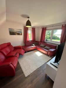 a living room with a red couch and red curtains at Kuestenkind in Lobbe