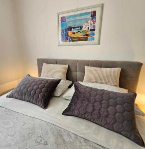 łóżko z dwoma poduszkami i obrazem na ścianie w obiekcie Apartmani Rita Kiwi w mieście Novigrad