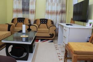 a living room with chairs and a tv and a table at Chaka Furnished Apartments in Kiganjo