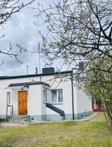 una casa blanca con una puerta marrón y un patio en Traditional White House with private garden and free parking, en Tomaszów Mazowiecki