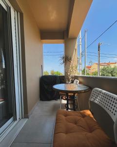 uma pequena varanda com uma mesa e um sofá em Liakada Guest House em Artemida