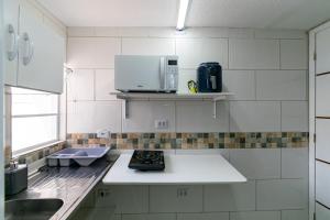 a white kitchen with a microwave and a sink at 53 LOFT Quadruplo · LOFT 900m da São Paulo Expo e do metrô Jabaguara in Sao Paulo