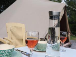 twee glazen wijn zittend op een tafel bij Beautiful safari tent in Twijzel with terrace in Twijzel