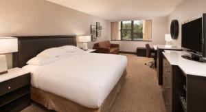サラトガ・スプリングズにあるThe Saratoga Hiltonの大きなベッドとデスクが備わるホテルルームです。
