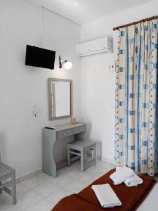 uma casa de banho com um lavatório e um toucador com um espelho. em Dennis Apartments em Kalamaki