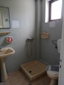 uma casa de banho com um chuveiro, um WC e um lavatório. em Dennis Apartments em Kalamaki