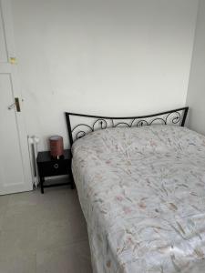 a bed in a bedroom with a white wall at Appartement près de la Gare RIS ORANGIS in Ris-Orangis