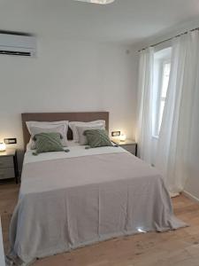 a white bedroom with a large bed and a window at House Mvsevm 4* in Vis
