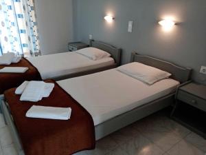 two beds in a hotel room with towels on them at Dennis Apartments in Kalamaki