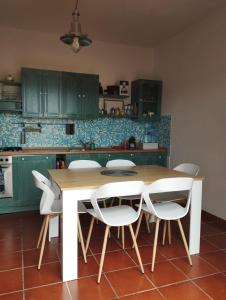 a kitchen with a wooden table and white chairs at Poppy's House in Torre Dei Corsari