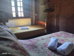 a bedroom with two beds with towels on them at Chalé Castelo Interlagos in Santo Amaro