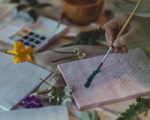a person painting a piece of paper with a paintbrush at Dinso Resort & Villas Phuket, Vignette Collection, an IHG Hotel in Patong Beach
