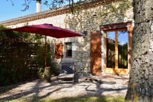 a red umbrella sitting in front of a house at Le Vignal in Monflanquin