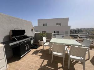 un patio con parrilla, mesa y sillas en Amazing Spacious Apartment with BBQ & Jacuzzi, en San Julián
