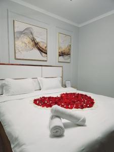 un lit avec un bouquet de roses rouges sur le lit dans l'établissement LUXE APARTMENTS, à Almaty